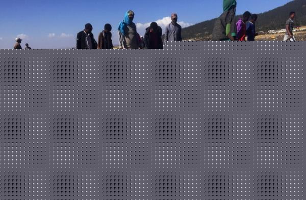 People walk past a part of the wreckage at the scene of the Ethiopian Airlines Flight ET 302 plane crash