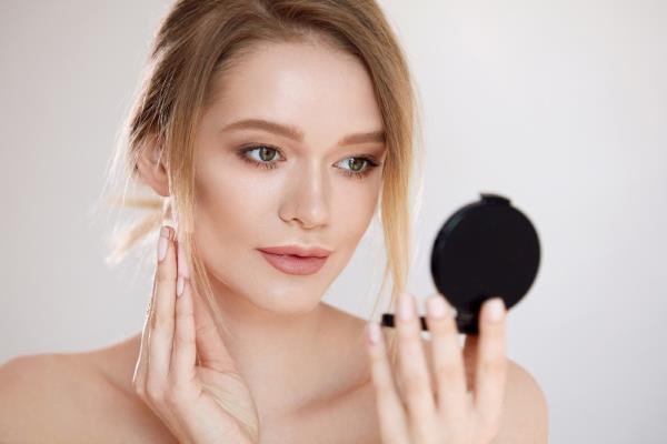 Closeup shot of a woman using a cuticle pusher to give a nail manicure. Nail technician giving customer a manicure at nail salon. Young caucasian woman receiving a french manicure